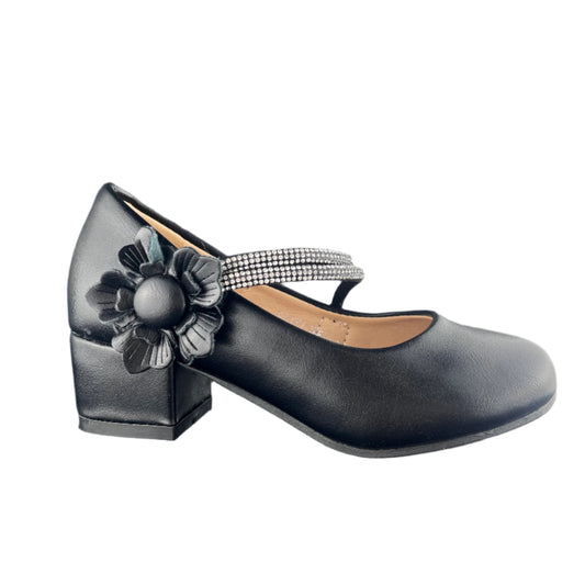 Black shoe with a decorative flower and strap on a dark surface